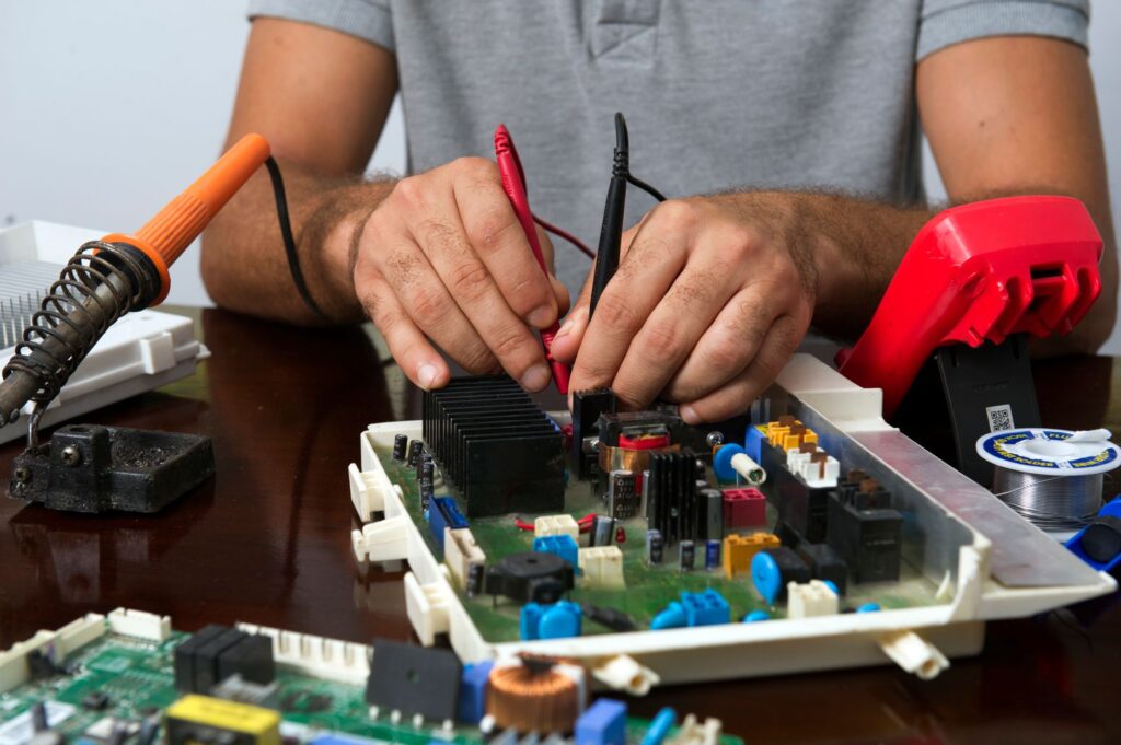 Appliance repair technician testing a washing machine control board with a multimeter
