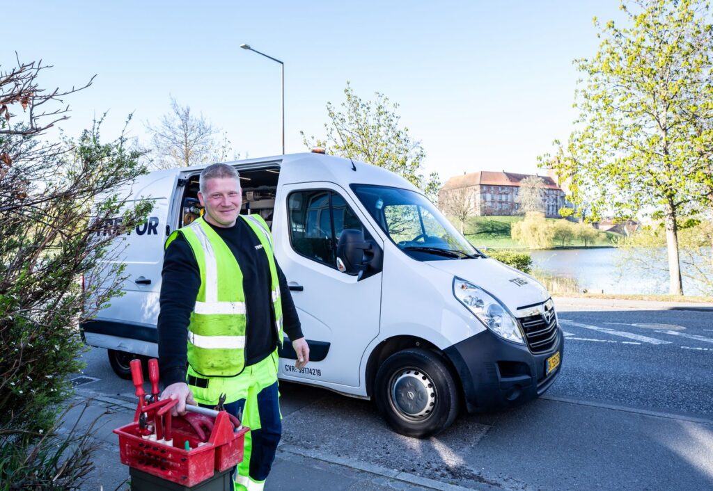 Smiling appliance repair technician in hi-vis vest standing beside a white service van with tools, ready for a same-day service call in Frisco TX