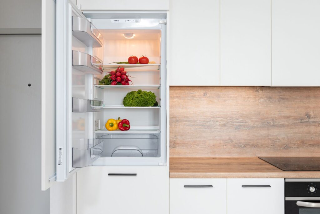 Open refrigerator stocked with fresh vegetables in a bright modern kitchen — illustrating the importance of fast appliance repair in Frisco TX