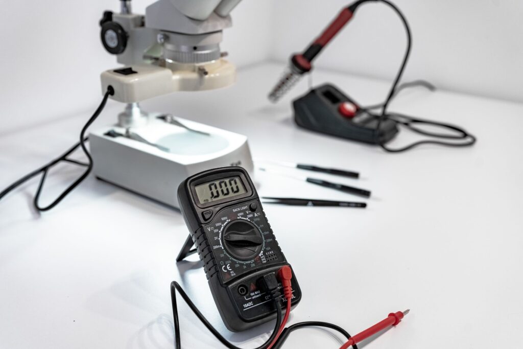 Digital multimeter with red and black test probes on a workbench, ready for resistance testing