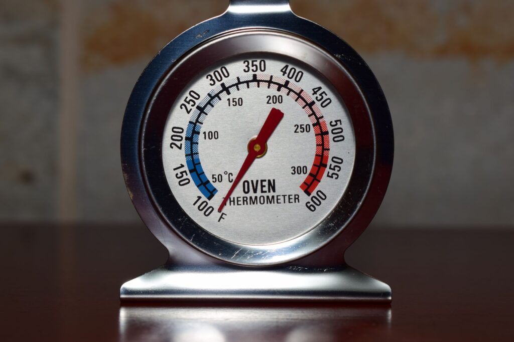 Close-up of a round dial oven thermometer showing temperature in both Fahrenheit and Celsius