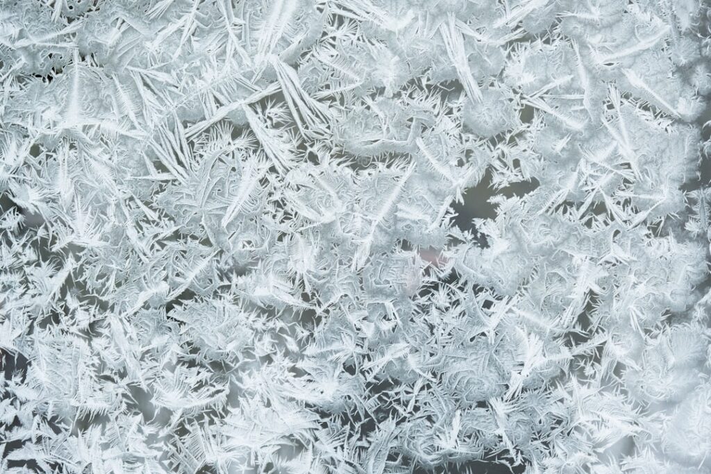 Close-up of frost and ice crystal formations showing typical buildup patterns in freezer defrost systems